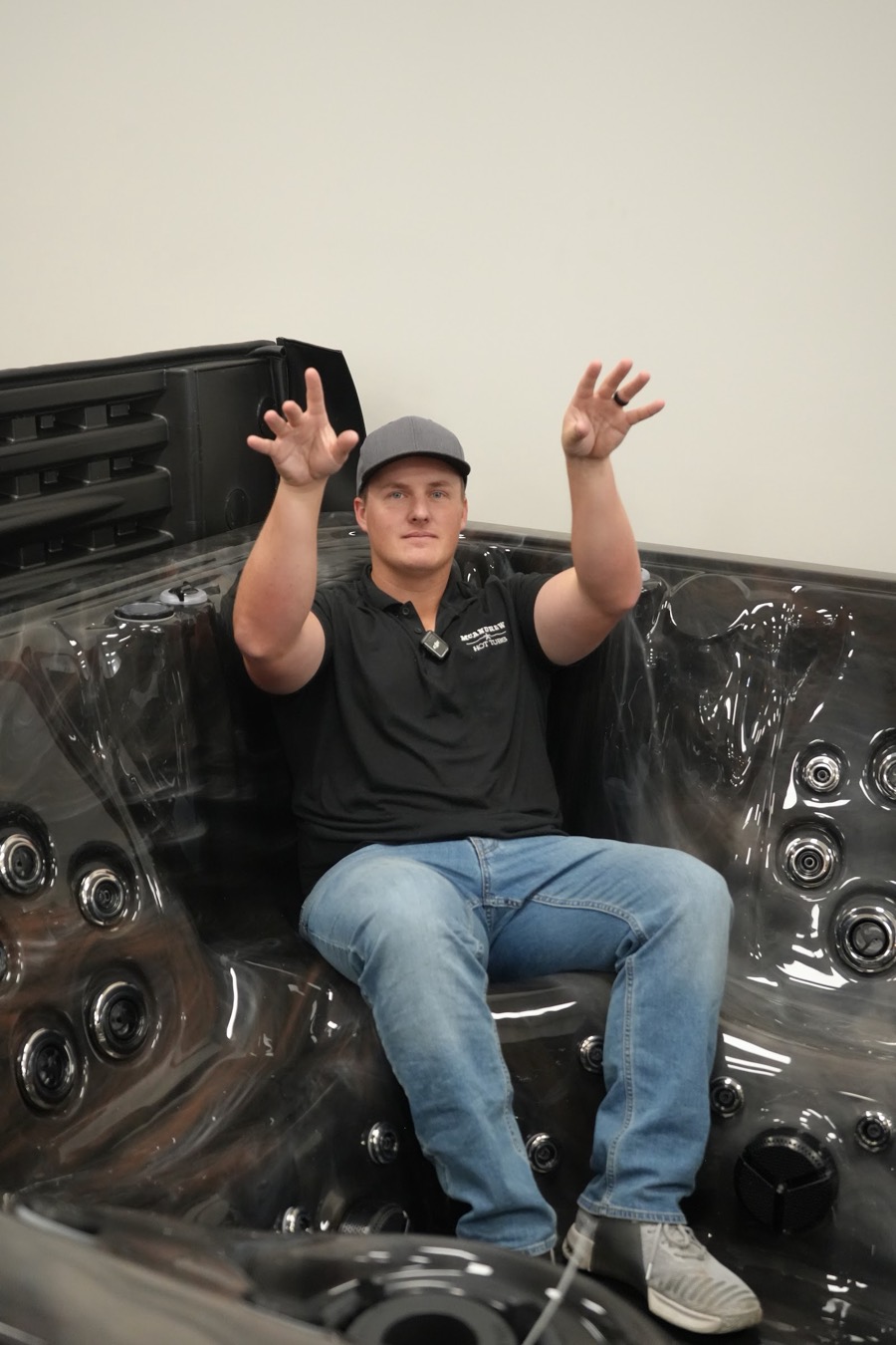 Team member seated in a hot tub on the showroom floor holding a beach ball